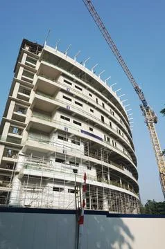 Curved building construcion facade in progress with tall crane Stock Photos