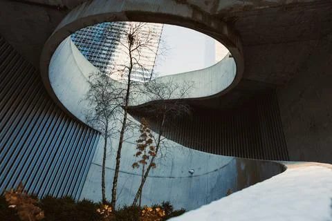 Curved concrete structure with trees under a clear sky in a city during day.. Stock Photos