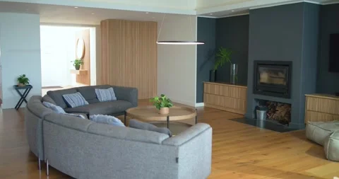 Curved gray sectional sofa occupying left side in modern living room, showcasing Vídeos de archivo 340393031