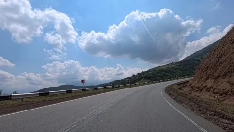 Curved highway winds through rocky hills under partly cloudy skies Stock Footage 340078869