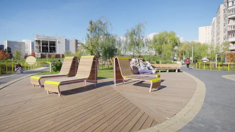 Curved lounge benches stand on deck in residential park Видео 331415010