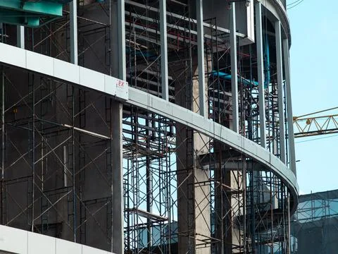 Curved modern building under construction with steel scaffolding, concrete .. Fotos de archivo