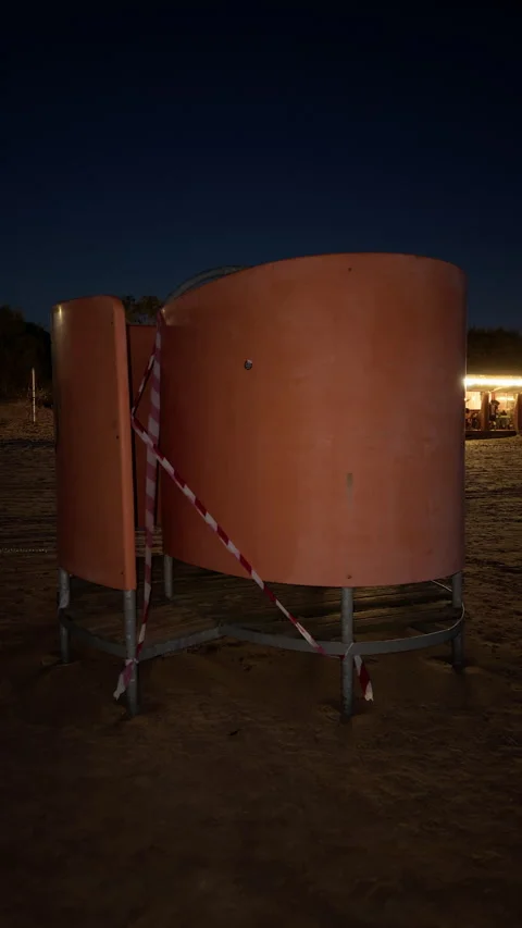 Curved orange structure on beach at night with caution tape and warm lights in Stock Footage 345123528