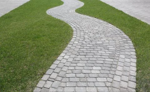 Curved path in the shape of a wave on the grass in the Park. Paved with tiles Stock Photos