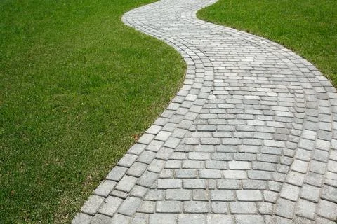 Curved path in the shape of a wave on the grass in the Park. Paved with tiles Stock Photos