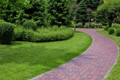 Curved pathway paved brick stone tiles in park. Stock Photos