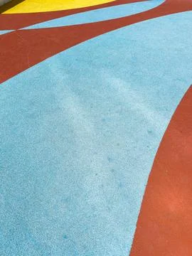 Curved patterns in red, blue, and yellow cover the rubber flooring of a playg Stock Photos