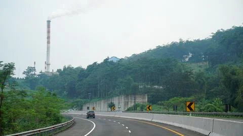 The curved road of the Trans Java Toll Road during the day, factory chimney.. Stock Photos