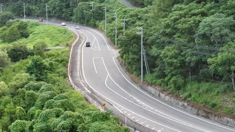 Curved road winds through lush green hills 库存影片 343249976