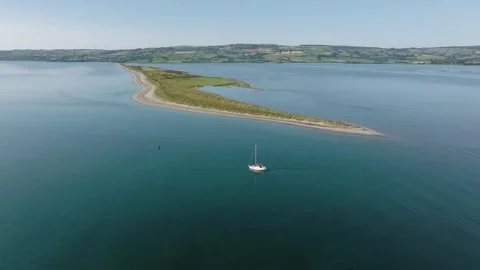 Curved Sand Spit and Lone Yacht in Still Irish Bay, Drone Flyover 스톡 동영상 347663653