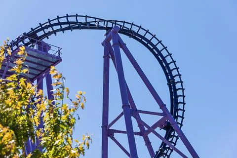 The curved section of a purple-blue rollercoaster against a blue sky. The most Foto stock