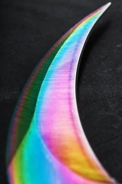 The curved sharp blade of the Kerambit Dagger is a gradient rainbow color on  스톡 사진