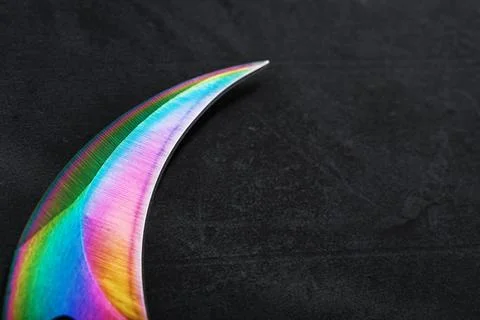 The curved sharp blade of the Kerambit Dagger is a gradient rainbow color on  Foto stock