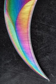 The curved sharp blade of the Kerambit Dagger is a gradient rainbow color on  스톡 사진