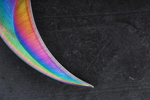 The curved sharp blade of the Kerambit Dagger is a gradient rainbow color on  스톡 사진