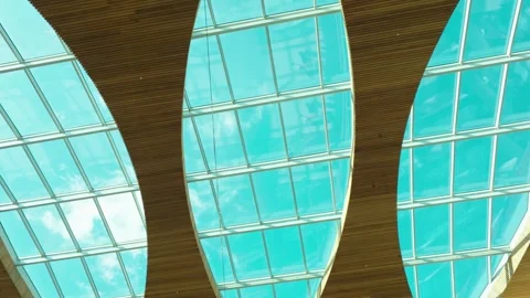 Curved skylight ceiling inside retail center with moving clouds visible through Stockbeeldmateriaal 336310276