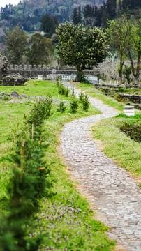 Curved stone pathway through green landscape with trees and ruins Stock Photos