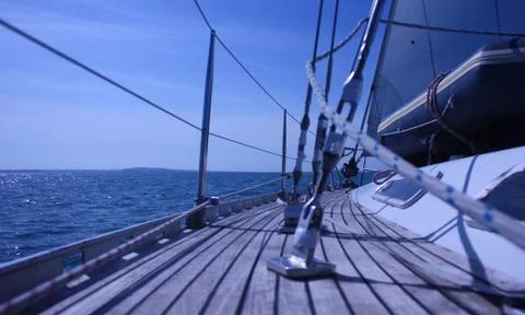The curved teak deck of a yacht sailing at sea Stock Photos