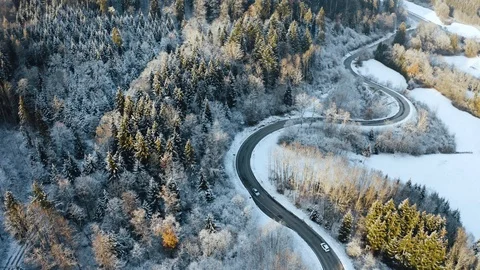 Curved winter road street between snow and forest trees on sunset. Cars driving Stock Footage 102812724