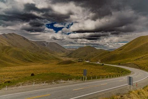 Curving Highway Through Dramatic Cloudy Mountain Valley Foto stock