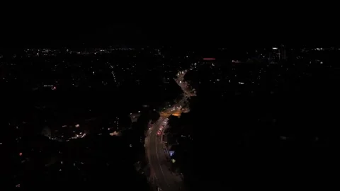 Curving main road glows through dark American suburb at night, streetlights and 스톡 동영상 347700857