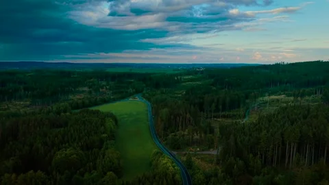 Curving road cutting through green forest under dramatic evening sky. Winding Stock Footage 323594792