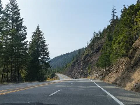 A curving rural highway bordered by cliffs and lush trees Stock Photos