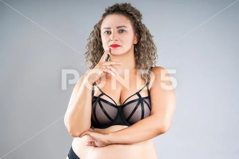 Curvy busty plus size model in push up bra on gray background