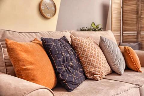 Cushions with pattern, grey and orange on sofa indoors, closeup Stock Photos