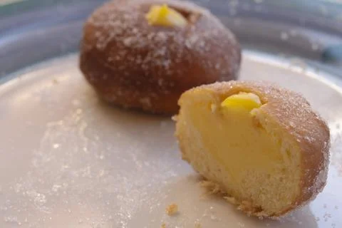 Custard filled doughnut half with sugar on a white plate Stock Photos