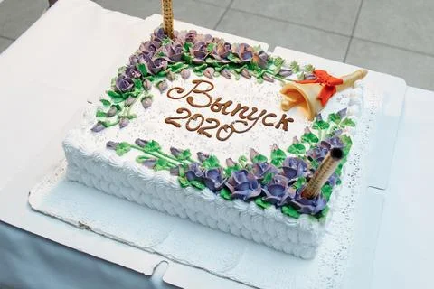 Custom 2020 graduation cake featuring white frosting, purple cream flowers, and Stock Photos