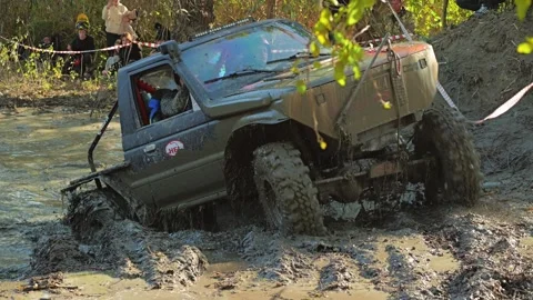 Custom off-road vehicle churning through thick mud and water during Stock Footage 345495437