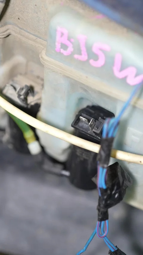 Custom wiring harness connected to a plastic windshield washer tank. Stock Footage 345910229