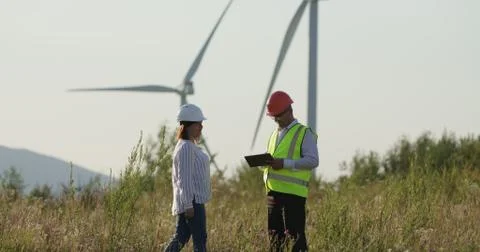 Customer and engineer looking at tablet to order. Windmills in the background Stock Photos