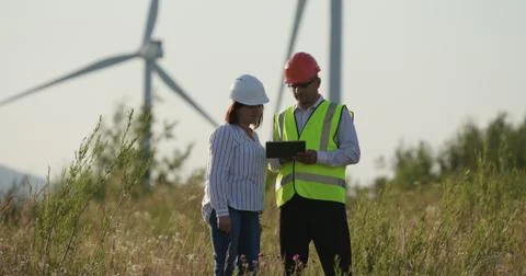 Customer and engineer looking at tablet to order. Windmills in the background Stock Photos