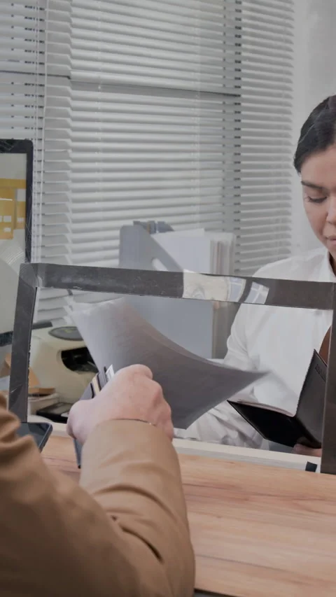 Customer and Teller Discussing Documents Across Divider Stock Footage 330960605