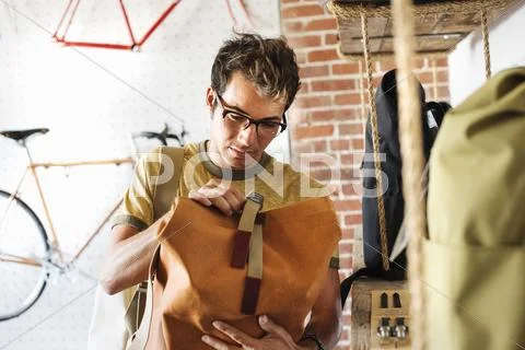 A customer in a bike shop, looking at a backpack. Stock Photos