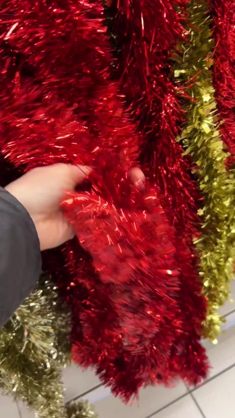 A customer browsing and selecting colorful Christmas garlands in a festive store Stock Footage 293639772