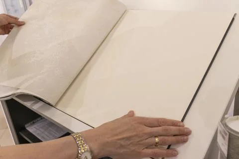 Customer Browsing Wallpaper Catalog Book in Modern Interior Design Showroom.. Stock Photos