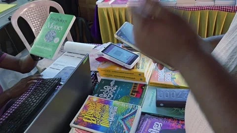 A customer buys a book at Kochi High Court station stall. They complete the digi Stock Footage 336440065