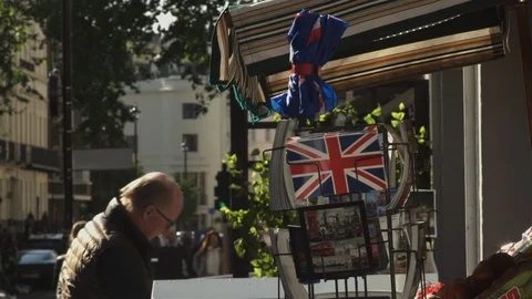 Customer buys newspaper on sunny London street Stock Footage 90082753