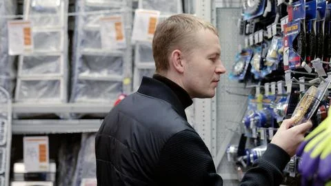 Customer carefully comparing tool models while reading package descriptions in a Stock Photos