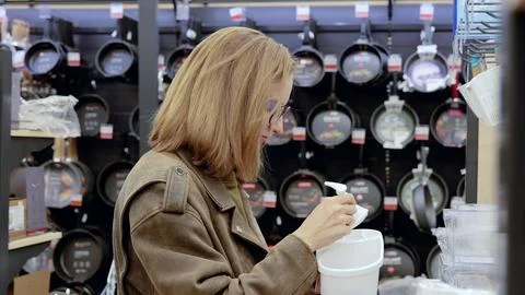 Customer carefully examining a plastic kitchen container with dispenser in a Stock Photos