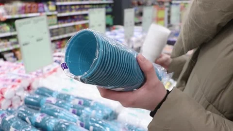 The customer chooses plastic cups in the store. Stock Footage 230175142