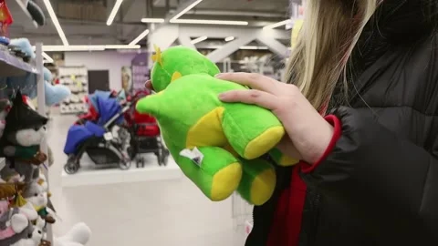 The customer chooses a soft toy. Mom chooses a soft toy - a dinosaur Stock-Footage 236649728