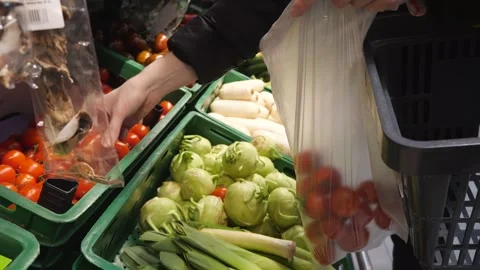 The customer chooses tomatoes and puts them in a bag in the store Stock Footage 267733194