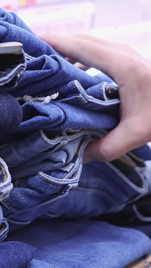 Customer choosing blue denim jeans in clothing store Stock Footage 343947308