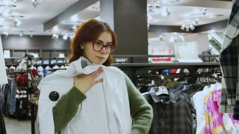 Customer choosing clothes holding white long sleeve shirt Video stock 282966605