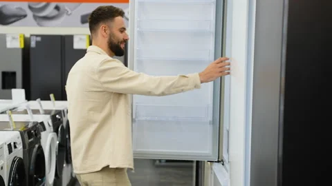 Customer choosing discounted refrigerator in electronics store Stock Footage 317731364