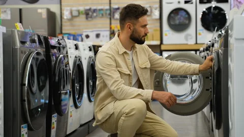Customer choosing discounted washing machine in electronics store Stock Footage 317731693